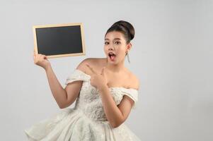 jeune belle mariée asiatique pose avec un tableau blanc à la main photo