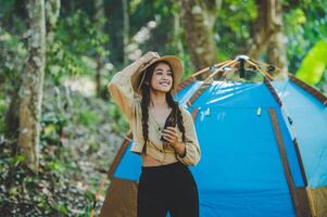 jeune femme applaudir et boire une boisson devant la tente de camping photo