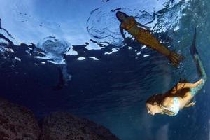 sirène nageant sous l'eau dans la mer d'un bleu profond photo