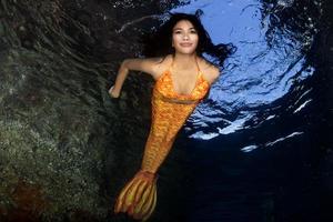 Orange queue Sirène nager sous-marin dans le Profond bleu mer photo
