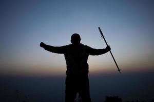 silhouette de applaudissement randonnée homme ouvert bras à le lever du soleil supporter sur Montagne photo