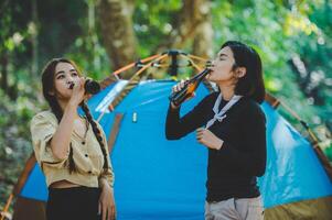 jeune femme applaudir et boire une boisson devant la tente de camping photo