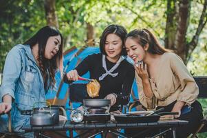 jeune femme cuisinant avec des œufs en camping avec une petite amie photo