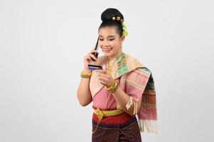 Jeune magnifique femme dans nord-est robe utilisation téléphone intelligent et crédit carte posture photo