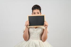 jeune belle mariée asiatique pose avec un tableau blanc à la main photo