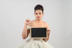 jeune belle mariée asiatique pose avec un tableau blanc à la main photo