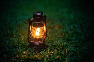 lampe à huile antique sur l'herbe dans la forêt dans l'atmosphère de camping du soir. image de concept de plein air de voyage photo