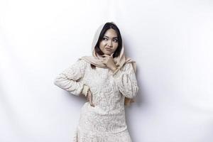 une réfléchi Jeune asiatique musulman femme portant hijab tandis que à la recherche de côté, isolé par une blanc Contexte photo