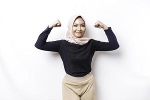 femme musulmane asiatique excitée portant un hijab montrant un geste fort en levant les bras et les muscles en souriant fièrement photo