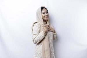 content conscient reconnaissant Jeune asiatique musulman femme avec sa main sur sa poitrine souriant isolé sur blanc Contexte photo