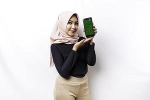 une portrait de une content asiatique musulman femme portant une hijab, montrant sa téléphone filtrer, isolé par blanc Contexte photo