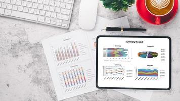 tablette avec graphiques et rapports sur le lieu de travail de bureau. vue de dessus mise à plat photo