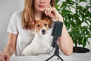 femme enregistrement Podcast avec une chien. éloigné travail à maison. animal de compagnie se soucier photo