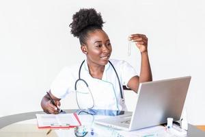 femme médecin en blouse blanche tenant des tubes à essai sanguin dans les mains tout en travaillant dans un laboratoire moderne. femme professionnelle des sciences de la vie tenant une cuvette en verre. concept de soins de santé et de biotechnologie. photo