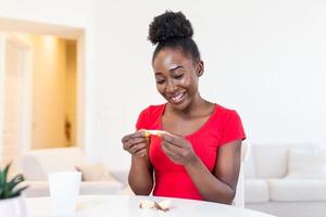 Jeune africain américain femme est en train de lire une message de fortune biscuits, Est-ce que le papier à l'intérieur de le biscuits dire vous bien des choses ou photo
