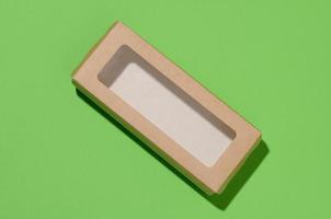 rectangulaire papier carton boîte avec une transparent Plastique couvercle sur une vert arrière-plan, Haut vue photo