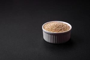 sain brut quinoa dans une bol sur une foncé béton Contexte photo