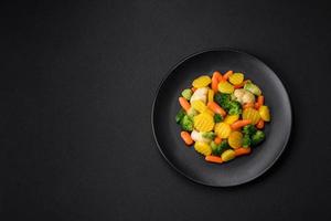 délicieux Frais des légumes à la vapeur carottes, brocoli, choufleur sur une noir assiette photo