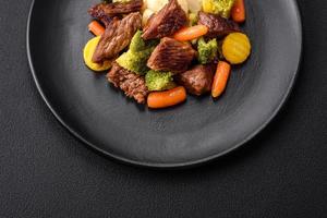 délicieux Frais du boeuf et des légumes carottes, brocoli, choufleur sur une noir assiette photo