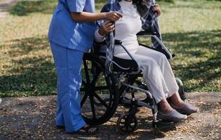 asiatique Jeune soignant infirmière soutien Sénior plus âgée Masculin en marchant en plein air. spécialiste fille médecin Aidez-moi et prendre se soucier de personnes âgées mature homme patient Faire physique thérapie dans Publique parc à allaitement maison. photo