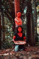 un asiatique femme et homme étaient permanent dans de face de une arbre tandis que chasse un animal dans le milieu de le forêt jusqu'à ce que elles ou ils étaient couvert dans du sang photo