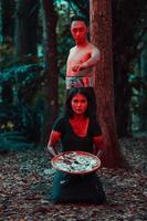 une couple de en série tueurs avoir corps couvert dans du sang et sont performant une satanique rituel dans le milieu de une forêt photo