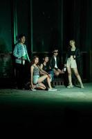 une groupe de adolescents dans excentrique vêtements posant ensemble comme copains dans une disco bar avec une très cool expression photo