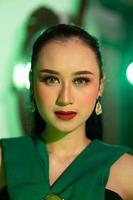 une magnifique asiatique femme dans une vert robe a une très exotique visage avec oreille et corps bijoux tandis que photo