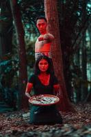 une couple de en série tueurs avoir corps couvert dans du sang et sont performant une satanique rituel dans le milieu de une forêt photo
