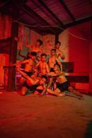 une groupe de Hommes sans pour autant vêtements dansant pose dans un vieux bâtiment avec une rouge lumière photo