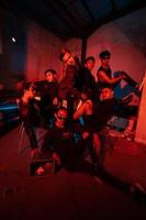 une groupe de asiatique adolescents dans noir vêtements posant très vilain avec leur copains dans une entrepôt avec une rouge lumière photo