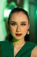 une magnifique asiatique femme dans une vert robe a une très exotique visage avec oreille et corps bijoux tandis que photo