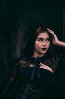 un asiatique adolescent a une effrayant apparence avec tout noir maquillage et une noir robe comme une sorcière avant Halloween photo
