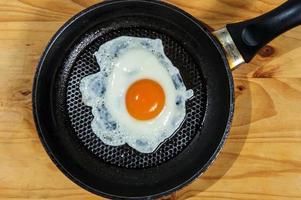 cuisine rôti des œufs pour petit-déjeuner, un autre Oeuf est conduit dans la poêle pour frit des œufs. photo