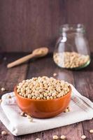 brut soja des graines dans une bol, cuillère et pot sur le tableau. la source de légume protéine. verticale vue photo