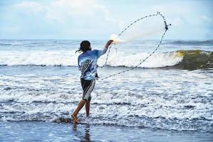 pêcheur moulage net sur tropical plage photo