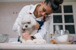 femme dans la cuisine pétrit la pâte avec son chien photo