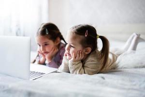 deux les filles sœurs en train de regarder sur portable. La technologie et Accueil concept. photo