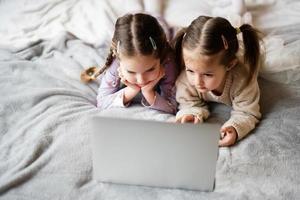 deux les filles sœurs en train de regarder sur portable. La technologie et Accueil concept. photo