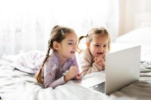 deux les filles sœurs en train de regarder sur portable. La technologie et Accueil concept. photo