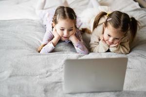 deux les filles sœurs en train de regarder sur portable. La technologie et Accueil concept. photo