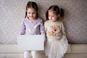 deux les filles sœurs en train de regarder sur portable. La technologie et Accueil concept. photo