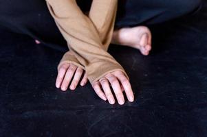 une homme est séance sur une noir sol. bras et jambes photo