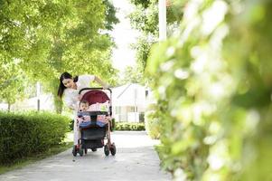 magnifique maman avec une bébé fille séance sur bébé chariot Extérieur dans ensoleillement journée photo