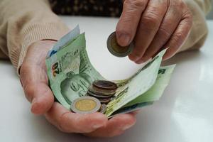 une femme âgée à la retraite comptant des pièces de monnaie et s'inquiète des dépenses mensuelles et du paiement des frais de traitement. photo