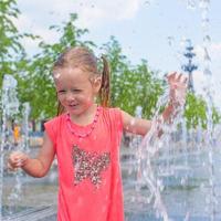 peu fille en jouant sur une l'eau Fontaine photo