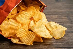 croustilles, délicieux assaisonnements pour barbecue épicés pour les crips, collations frites en fines tranches de restauration rapide dans un sac ouvert. photo