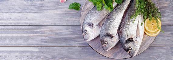 brut dorado poisson avec vert herbes cuisine sur Coupe planche. bannière. Haut vue photo