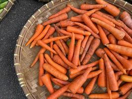 frais, biologique et imparfait carottes sur rond bambou plateau étant vendu à traditionnel marché photo