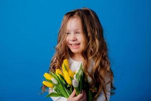 portrait de une charmant souriant peu fille avec une bouquet de tulipes dans sa mains. mode de vie. Frais fleurs. international aux femmes journée. espace pour texte. haute qualité photo